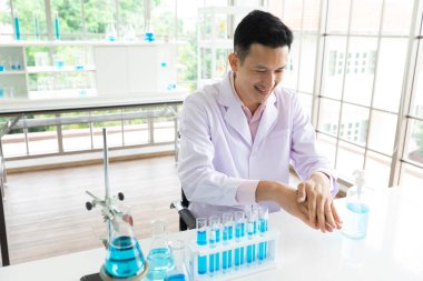 Genç bilim adamı laboratuvarda virüsü önlemek için ellerini alkol jeliyle yıkıyor.