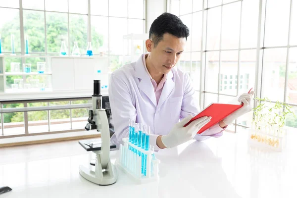 young man scientist reading a book sitting in laboratory