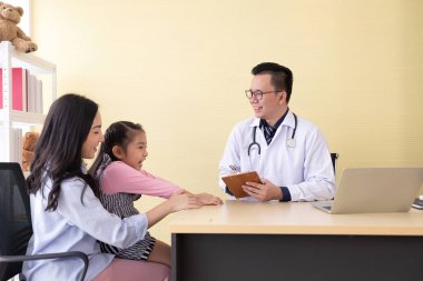 Asyalı doktor konuşuyor ve klinikteki anne ve çocuğa hasta bilgilerini soruyor.