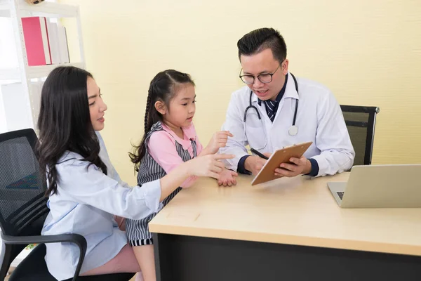 アジアの医師が診療所で子供や母親に患者の情報を聞き — ストック写真