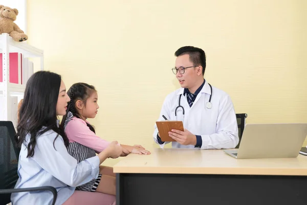 アジアの医師が診療所で子供や母親に患者の情報を聞き — ストック写真