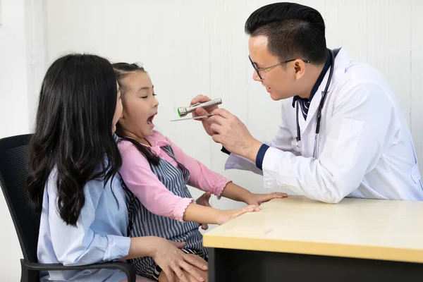 Asiático Médico Examinando Pequeña Niña Boca Con Lengua Depresor Madre —  Fotos de Stock