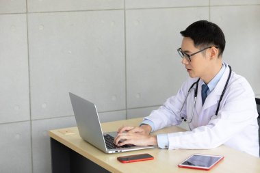 Hastanedeki bilgisayarla çevrimiçi görüntülü konuşma yoluyla Asyalı doktor ya da iş arkadaşı ile konuşuyor