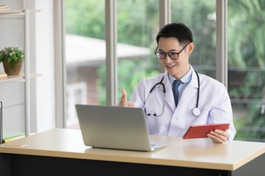 Hastanedeki bilgisayarla çevrimiçi görüntülü konuşma yoluyla Asyalı doktor veya meslektaşı ile konuşuyor.