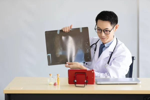 young doctor explaining about film x-ray(foot radiograph) with patient or co-worker through online video chat from tablet in hospital