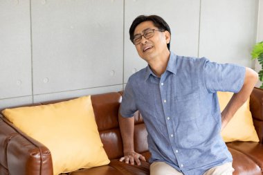 Sırtında ve belinde ağrı olan yaşlı Asyalı bir adam.