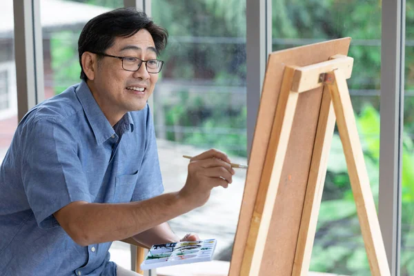 senior asian man painting at home