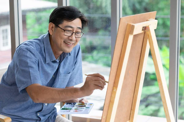 senior asian man painting at home