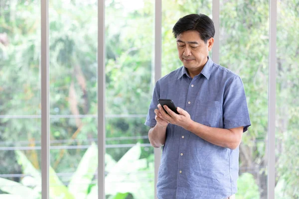 senior asian man try to understand how to using a smartphone at home