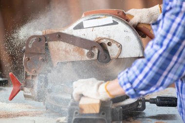 Kapalı el marangozu, atölyedeki bir tahta parçası üzerinde tahta kesmek için elektrikli testere kullanıyor.
