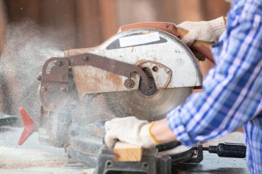 Kapalı el marangozu, atölyedeki bir tahta parçası üzerinde tahta kesmek için elektrikli testere kullanıyor.