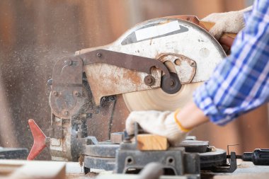 Kapalı el marangozu, atölyedeki bir tahta parçası üzerinde tahta kesmek için elektrikli testere kullanıyor.