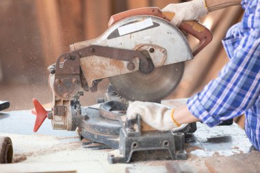 Kapalı el marangozu, atölyedeki bir tahta parçası üzerinde tahta kesmek için elektrikli testere kullanıyor.