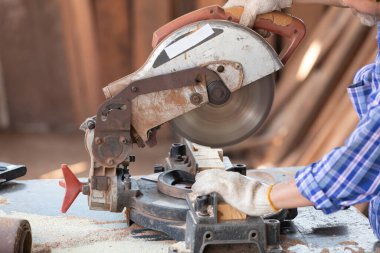 Kapalı el marangozu, atölyedeki bir tahta parçası üzerinde tahta kesmek için elektrikli testere kullanıyor.