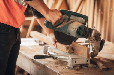 Kapalı el marangozu, atölyedeki ahşap bir parça üzerinde tahta kesmek için elektrikli testere kullanır.)