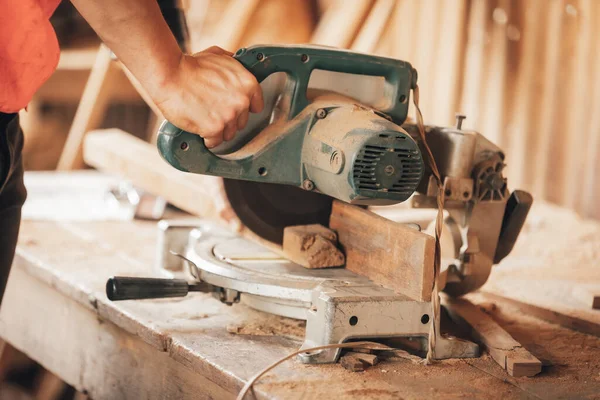 Worker hands details of wood cutter machine with a circular saw and wooden  board. Circular cutting saw in action. Stock Photo