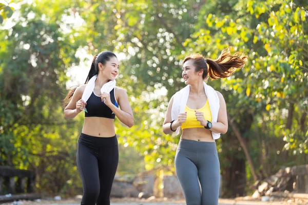 asian athletics couple woman jogging and exercising together in public park in the evening