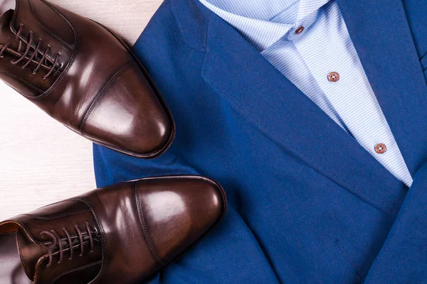 Conjunto de ropa clásica para hombre - traje azul, camisas, zapatos marrones, cinturón y corbata sobre fondo de madera. — Foto de Stock