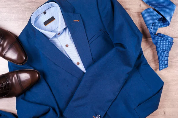Conjunto de ropa clásica para hombre - traje azul, camisas, zapatos marrones, cinturón y corbata sobre fondo de madera. — Foto de Stock