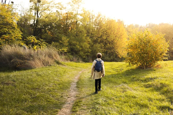 Sırt çantalı genç bir çocuk kırsal yolda yürüyor. Kader kavramı, yol seçimi.