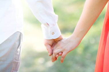 Mutlu çift gün batımında yeşil parkta el ele tutuşuyor.