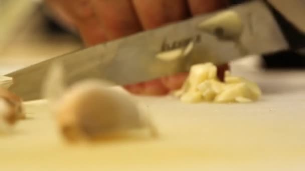 Hugga färsk vitlök med en vass kniv på en skärbräda på nära håll — Stockvideo