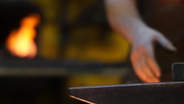 forgeron marteler métal chaud sur une enclume dans un atelier derrière lui une forge 