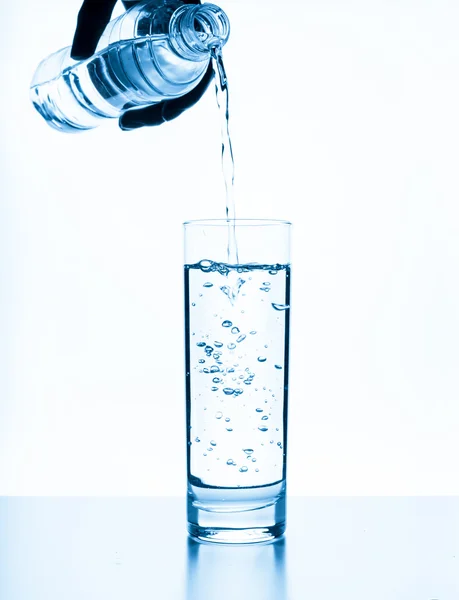 Agua vertiendo en vidrio aislado sobre fondo blanco — Foto de Stock