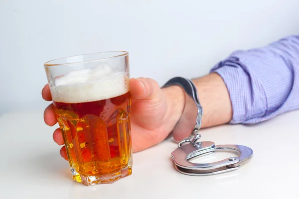 Рука с алкоголем и наручниками — стоковое фото