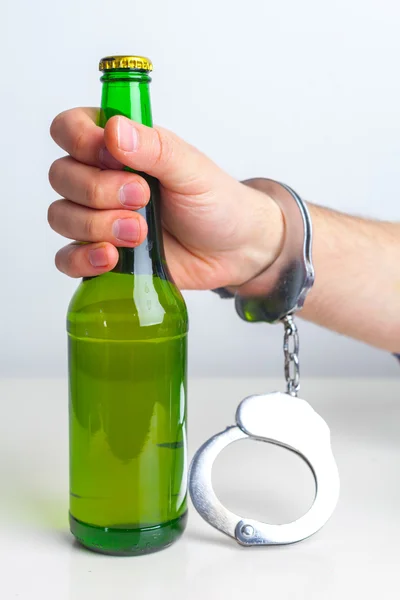 Стакан пива с наручниками в качестве символа злоупотребления алкоголем — стоковое фото