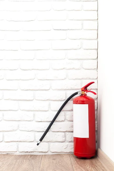 Fire extinguisher near white wall — Stock Photo, Image