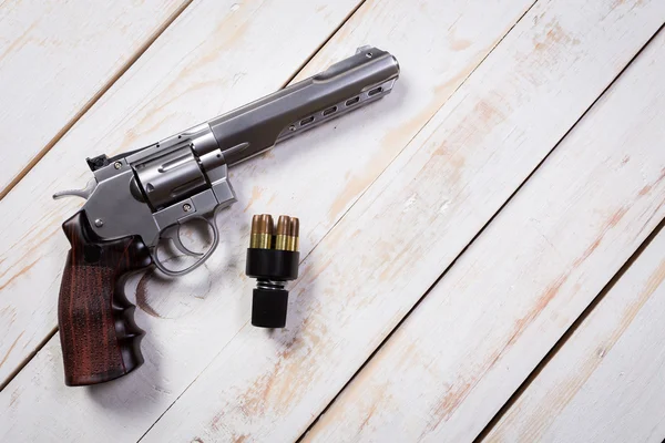 Ручной пистолет с патронами на деревянном столе — стоковое фото