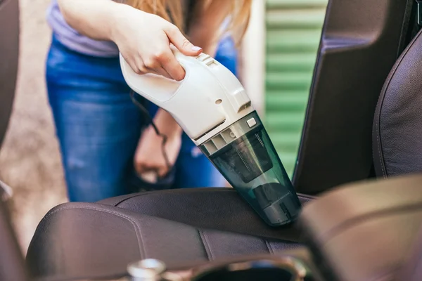 Vrouw schoonmaken interieur van auto met behulp van stofzuiger — Stockfoto