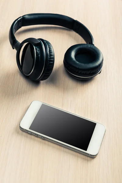 Kopfhörer und Telefon auf dem Schreibtisch — Stockfoto