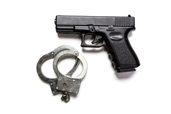 Черная пушка и наручники — стоковое фото