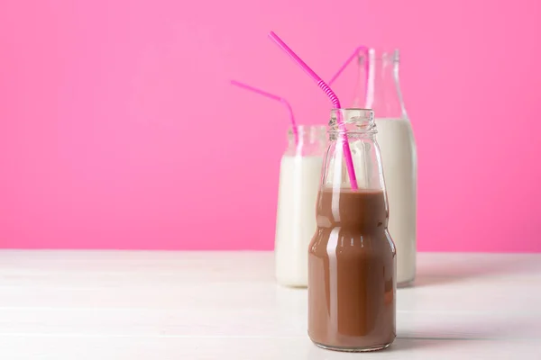 Frascos de vidrio con batidos aromatizados sobre fondo rosa — Foto de Stock