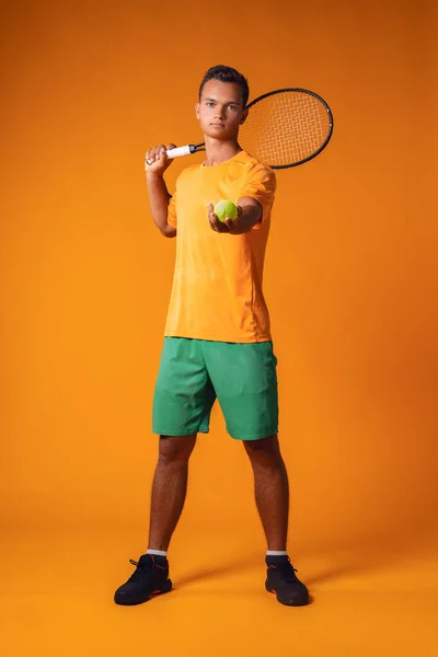 Retrato completo de un jugador de tenis en acción contra fondo naranja —  Fotos de Stock