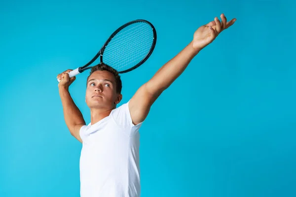 Young man tennis player in sportswear posing against blue background