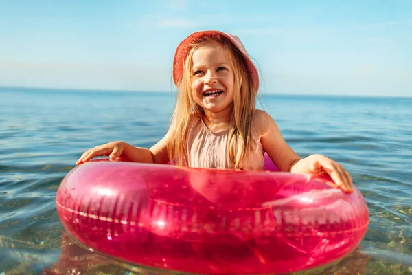 Jeune fille en panama rose nageant dans la mer avec cercle — Photo