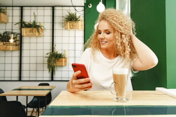 Linda mulher loira encaracolado tomando selfie enquanto sentado à mesa no café — Fotografia de Stock