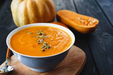 Siyah bir masada ev yapımı balkabağı çorbası.