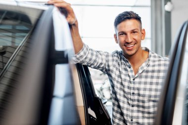 Neşeli genç adam bir galeriden yeni bir araba alıyor.