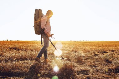 Metal dedektörlü bir adam arazide metal eşyalar arıyor.