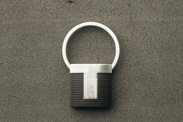 Μενταγιόν μεταλλικό κλειδί σε σκούρο φόντο από τσιμέντο — Φωτογραφία Αρχείου