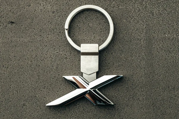 Metal letter X car key on dark concrete background