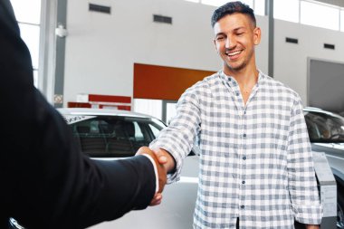 Neşeli genç adam bir galeriden yeni bir araba alıyor.