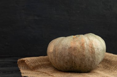 Siyah grunge arka planına karşı çuval bezi üzerinde gri balkabağı