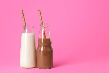 Pembe arka planda iki bardak süt ya da milkshake.