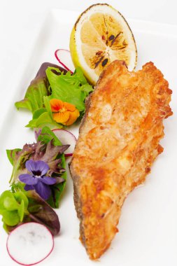 Beyaz arka planda otlu kızarmış balık filetosu.