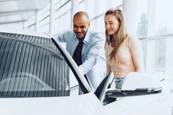 Junges glückliches Paar wählt Auto im Autohaus — Stockfoto